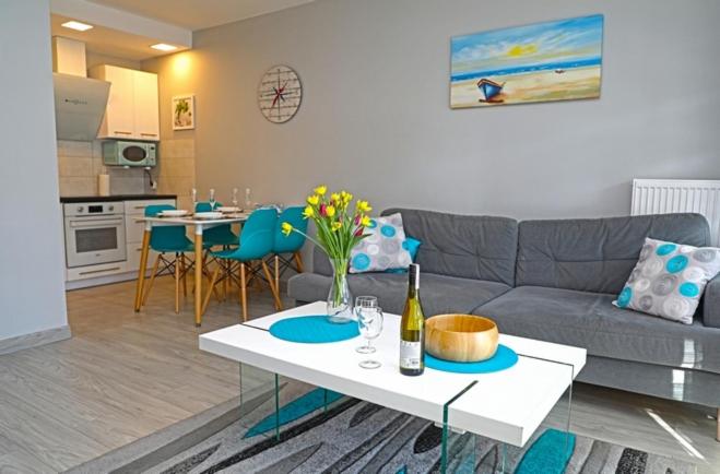 a living room with a couch and a table at Apartament BLUE BAY Darłówko in Darlowko