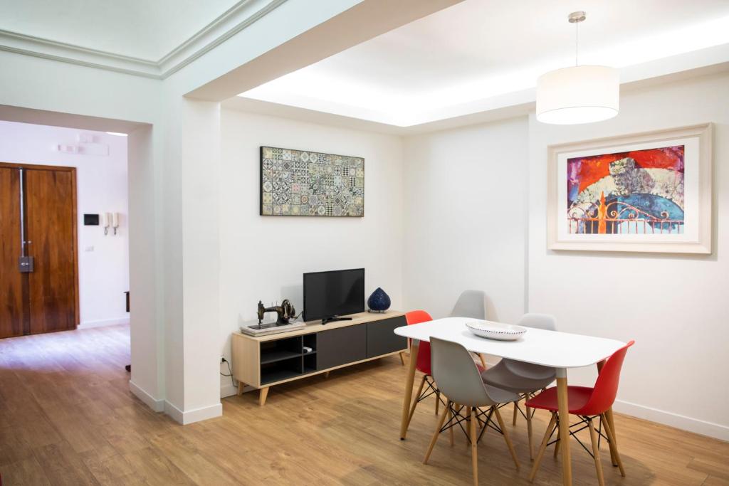 een woonkamer met een tafel en stoelen en een televisie bij Uzeda Inn Apartment in Catania