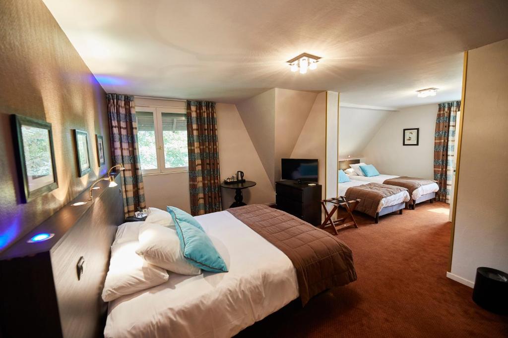 a hotel room with two beds and a television at La Flambée in Sennecey-lès-Dijon