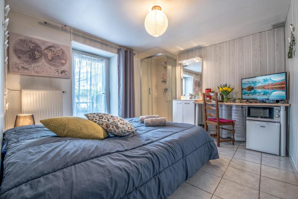 1 dormitorio con 1 cama con almohadas y cocina en La Savouè - Chambre en Francin