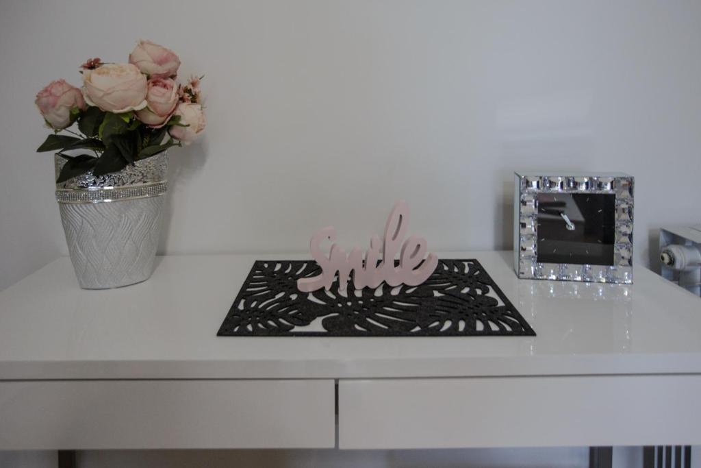 a white table with a vase of flowers and a picture at Apartman Kod Kestena in Osijek