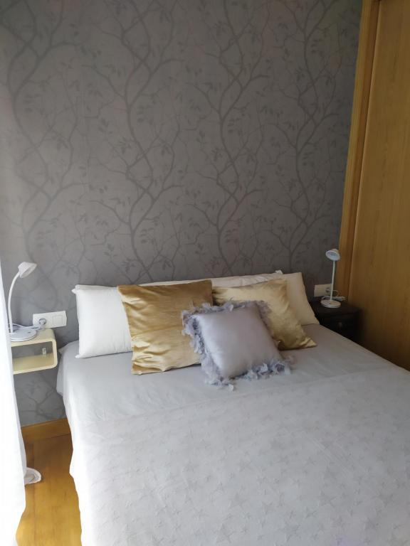 a bedroom with a bed with white sheets and pillows at APARTAMENTO BEATRIZ in A Pobra do Caramiñal