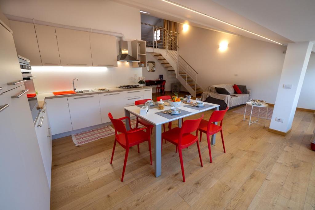 eine Küche und ein Esszimmer mit einem Tisch und roten Stühlen in der Unterkunft Mansarda Fogazzaro in Vicenza