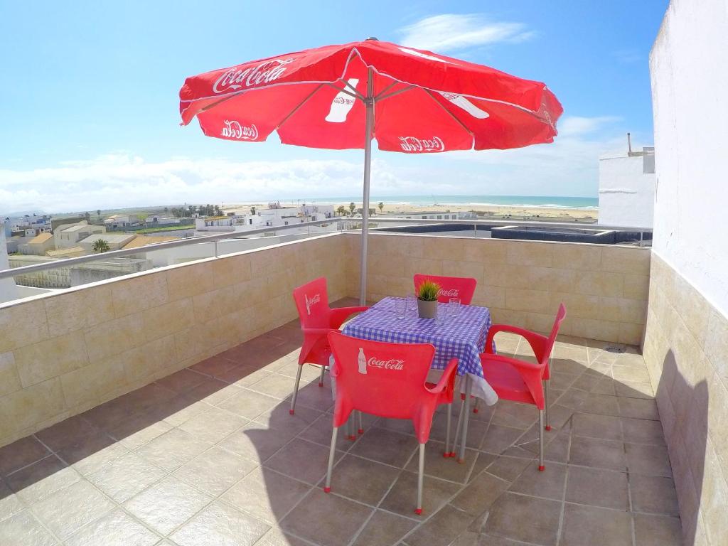 a table with a cocacola umbrella on a balcony at ConilPlus apartment SANTA CATALINA III in Conil de la Frontera