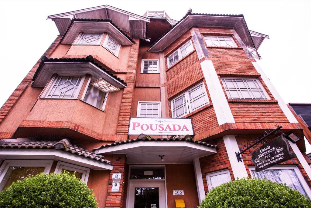 a tall red brick building with a sign on it at Grand Residences Pousadas in Campos do Jordão