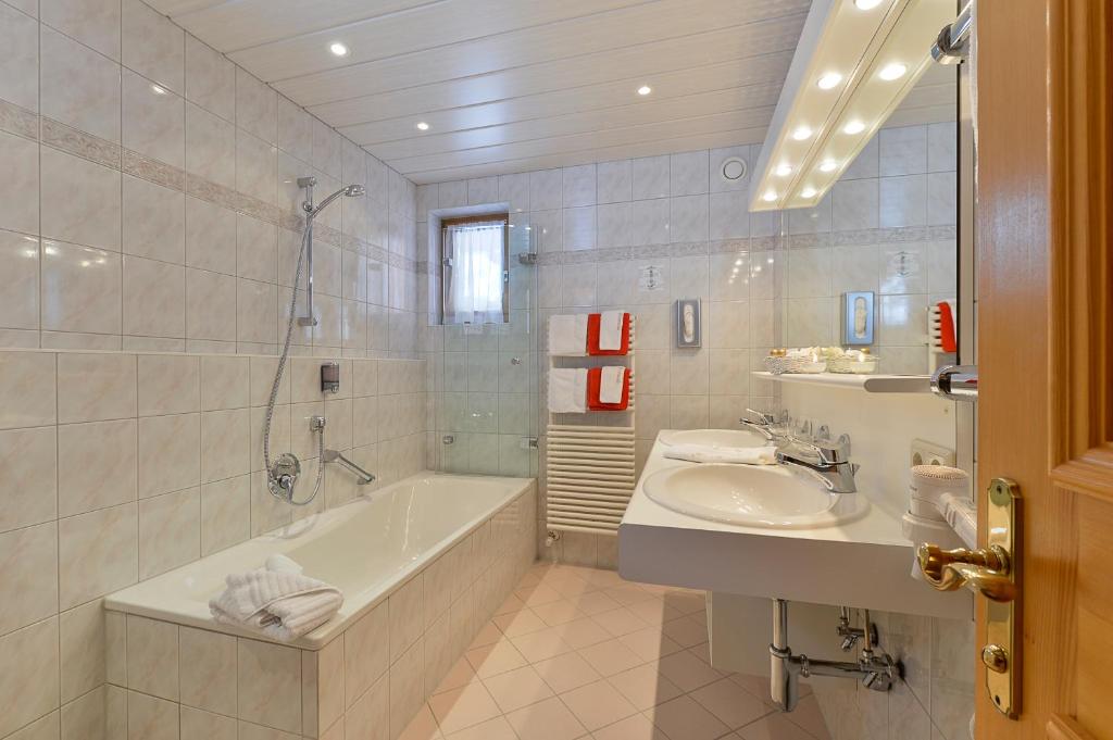 a white bathroom with a tub and a sink at Fürmesli Appartements in Lech am Arlberg