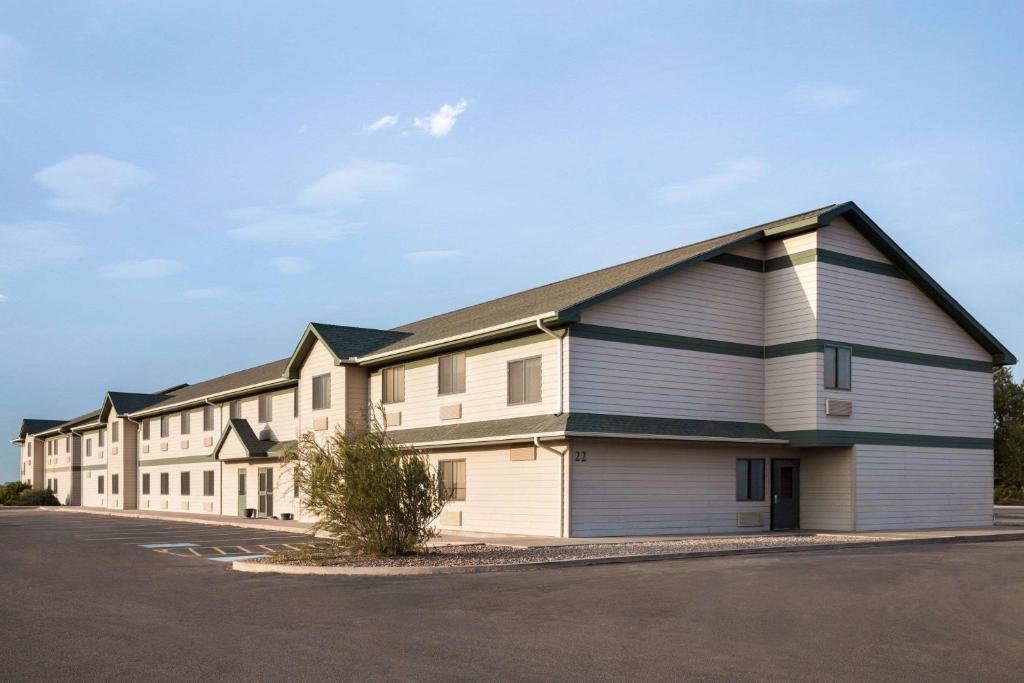 a large white building with a parking lot at Travelodge by Wyndham Pecos in Pecos