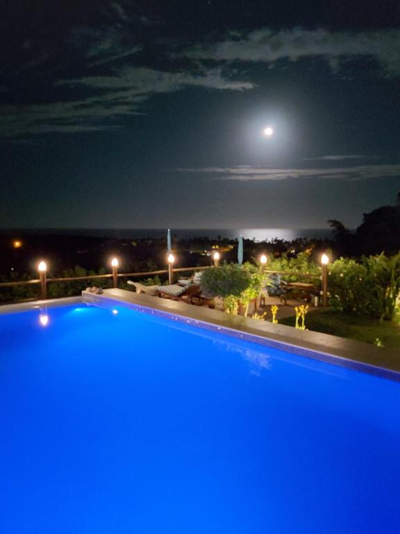 uma grande piscina azul à noite com a lua em Pousada Mar à Vista em Trancoso