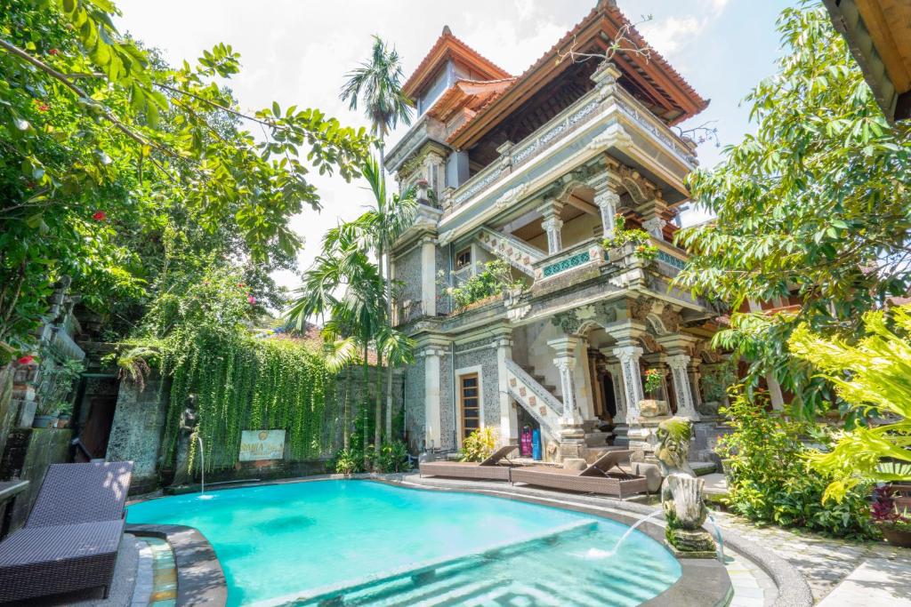 an old mansion with a swimming pool in front of it at Sania's House in Ubud