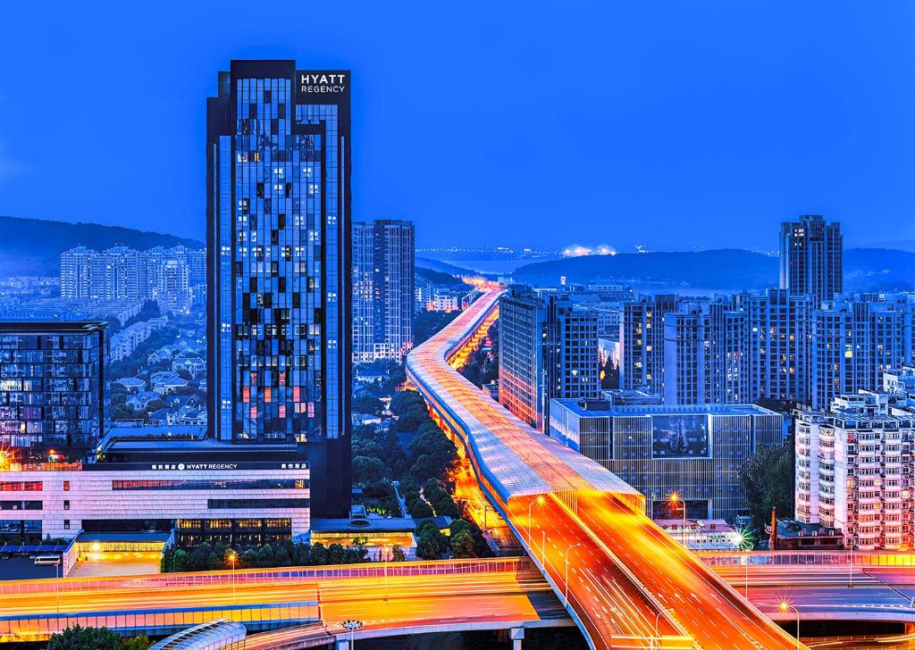 eine Skyline der Stadt bei Nacht mit Verkehr auf einer Autobahn in der Unterkunft Hyatt Regency Wuhan Optics Valley in Wuhan