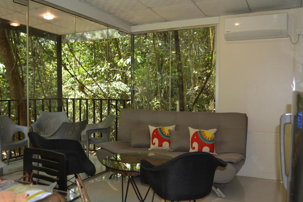 a living room with a couch and some chairs at Shadow Grove Camping & Cabins Kitulgala in Kitulgala