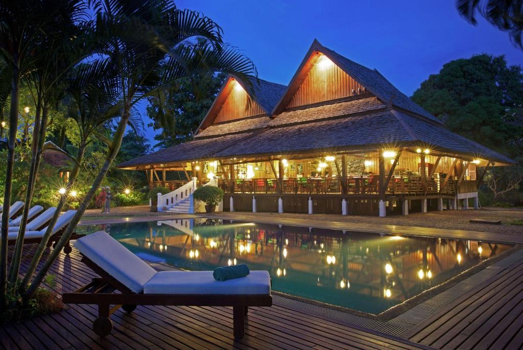 un complejo con piscina por la noche en La Folie Lodge, en Champasak