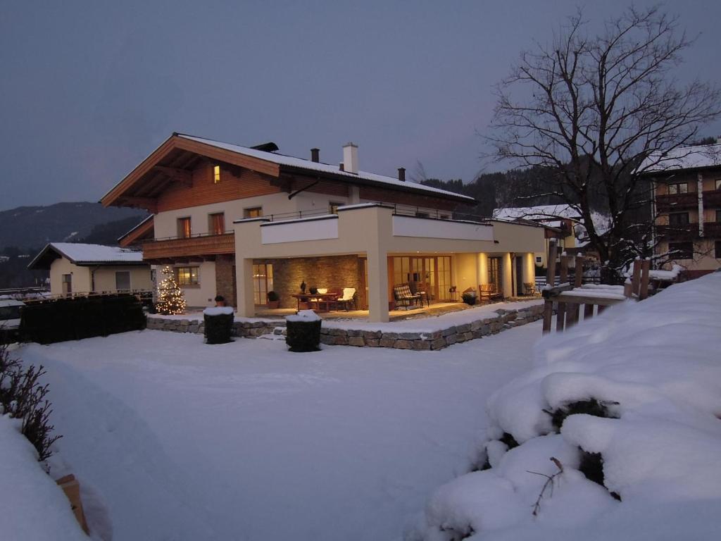 une maison avec une cour recouverte de neige devant elle dans l'établissement Alpine Active Weitgasser, à Flachau