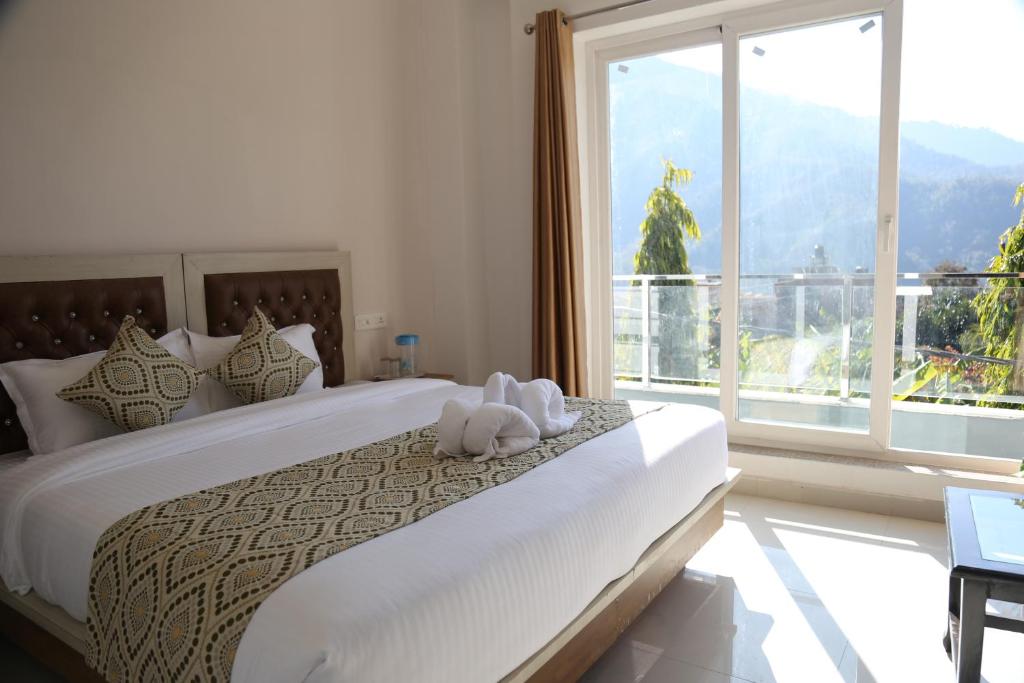 - une chambre avec un grand lit et une grande fenêtre dans l'établissement Mountain View Room By Yog Tapovan, à Rishikesh