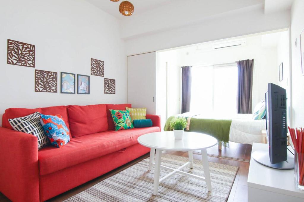 uma sala de estar com um sofá vermelho e uma mesa em Chiyo apartment em Fukuoka