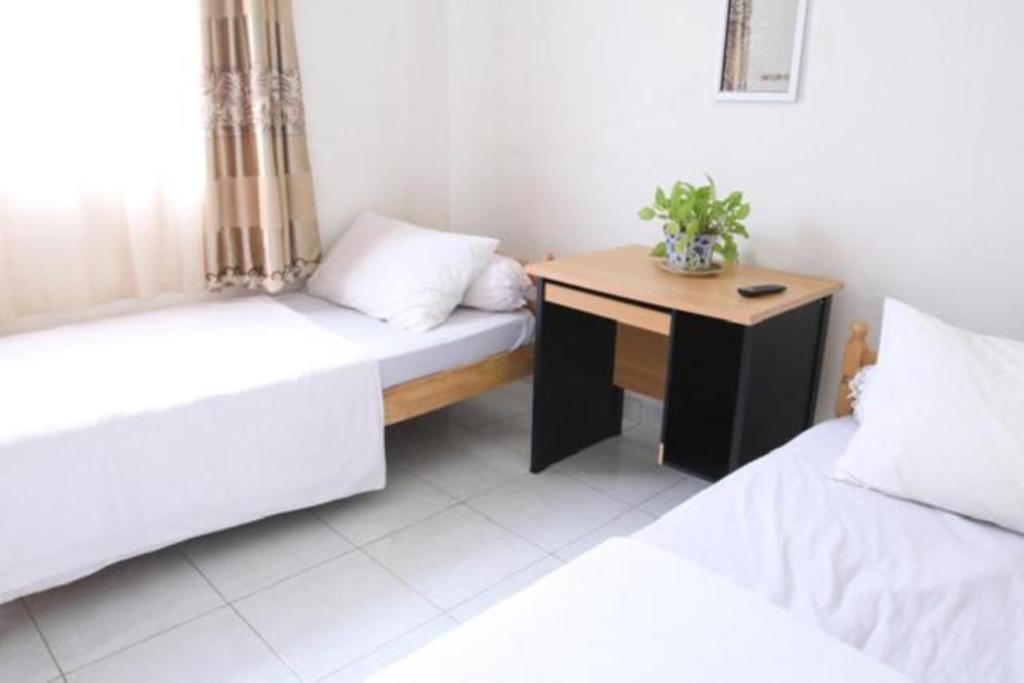 Cette chambre comprend 2 lits et une table en bois. dans l'établissement Rumah Kita, à Padang