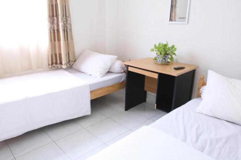 a room with two beds and a wooden table at Rumah Kita in Padang