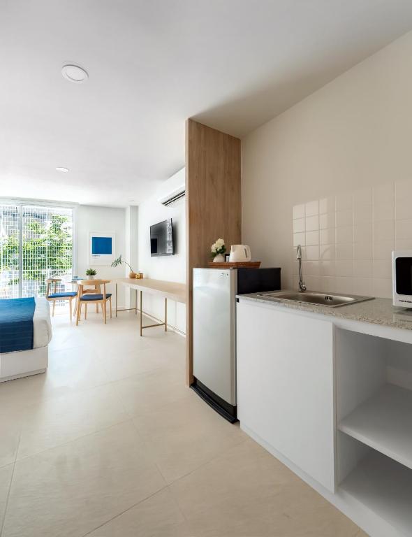 A wide view of a bright studio with kitchenette, seating and bed.