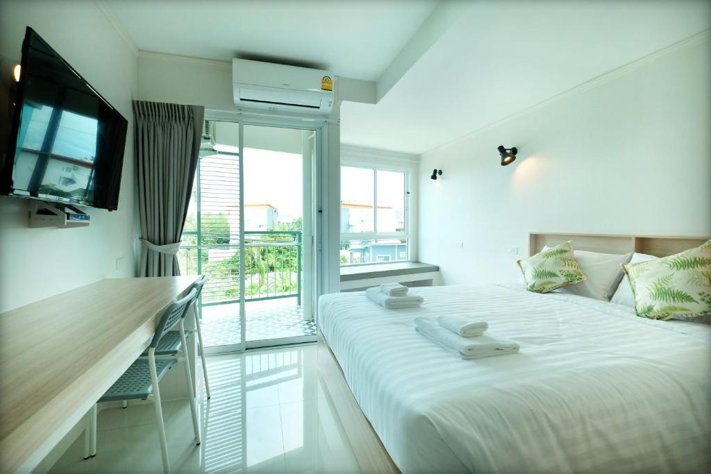a white bedroom with a bed and a balcony at beHOME Phuket in Nai Yang Beach