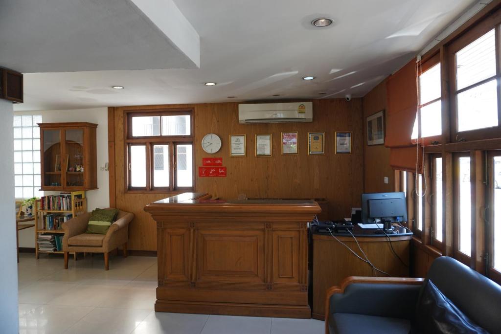 A wood-panelled reception lobby with a front desk, computer station and lounge seating.
