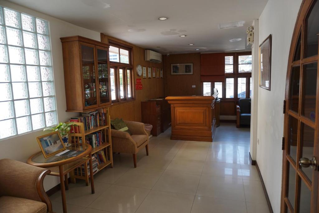 A long lobby corridor with lounge chairs, bookshelves and the reception desk at the far end.