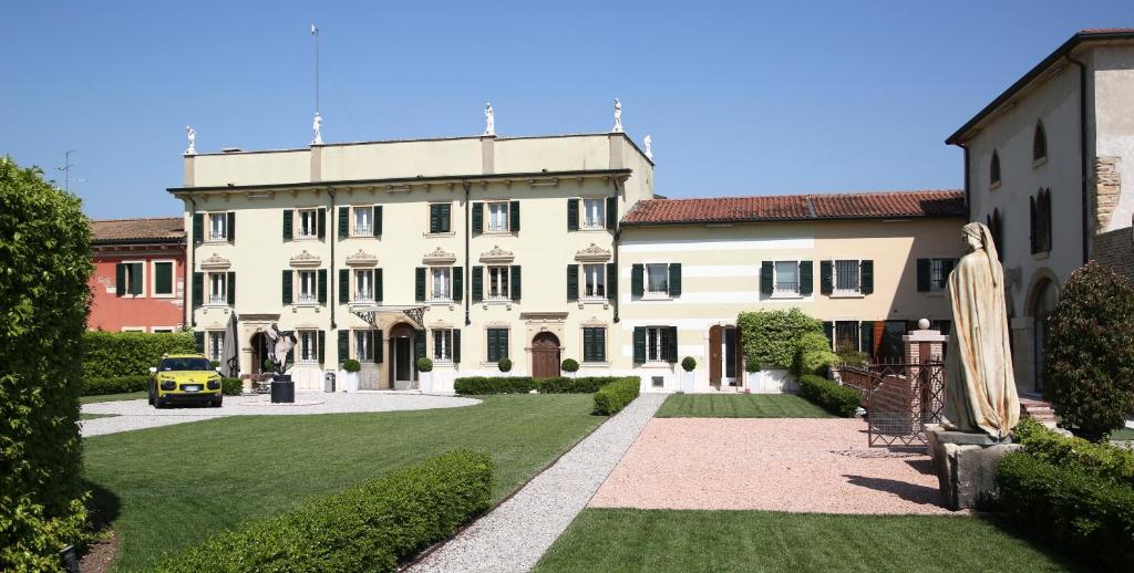 duży biały budynek z samochodem zaparkowanym na dziedzińcu w obiekcie Madonna Villa Baietta w Weronie
