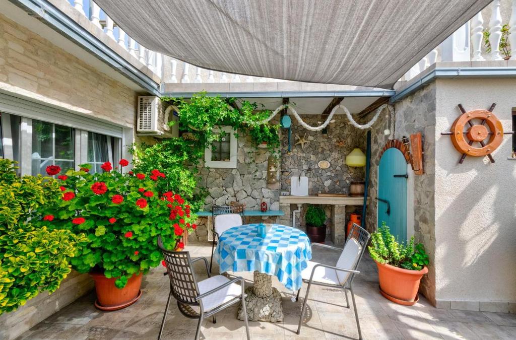 a patio with a table and chairs and flowers at TOMIC A MAZURANICA in Novi Vinodolski