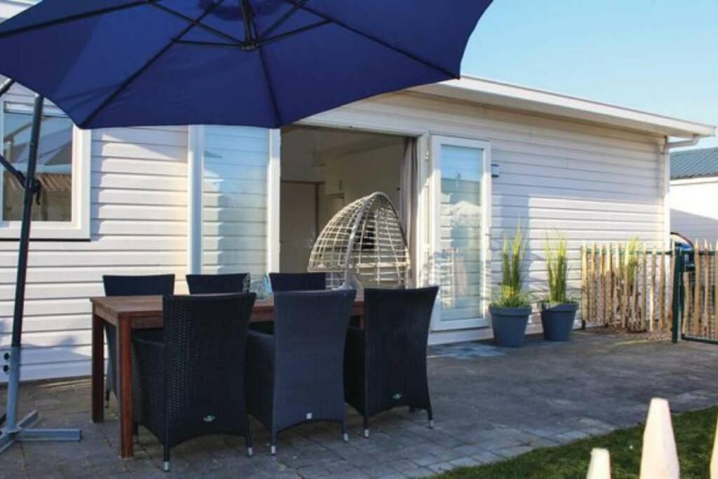 een tafel met stoelen en een blauwe parasol bij Vakantie met sauna in Zeeland in Sint Annaland