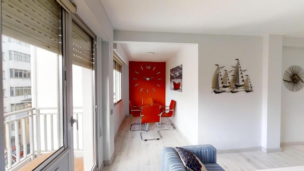 Apartamentos Design Pinemar في كاباناس: غرفة معيشة مع أريكة وجدار احمر