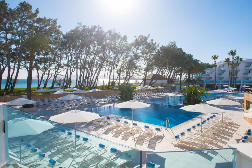 une grande piscine avec des chaises et des parasols dans l'établissement Iberostar Playa de Muro, à Playa de Muro