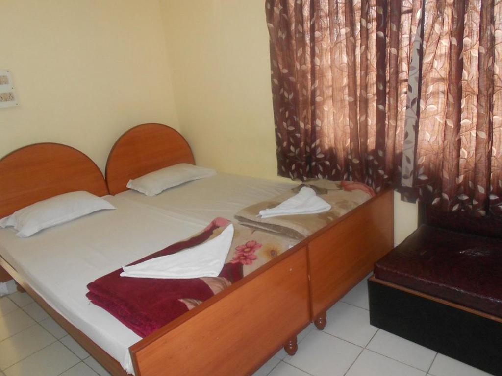 um quarto com uma cama de madeira e lençóis brancos em Hotel Geetanjali em Guwahati