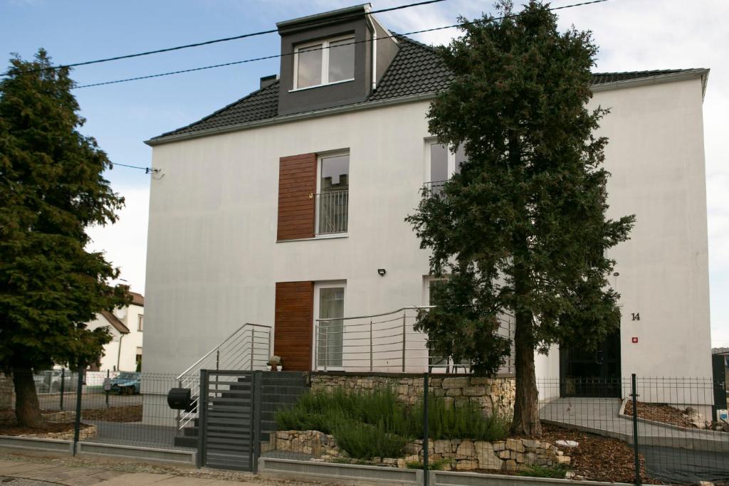 une maison blanche avec un arbre en face dans l'établissement Apartamenty Lawendowy Zakątek 2, à Carolinensiel