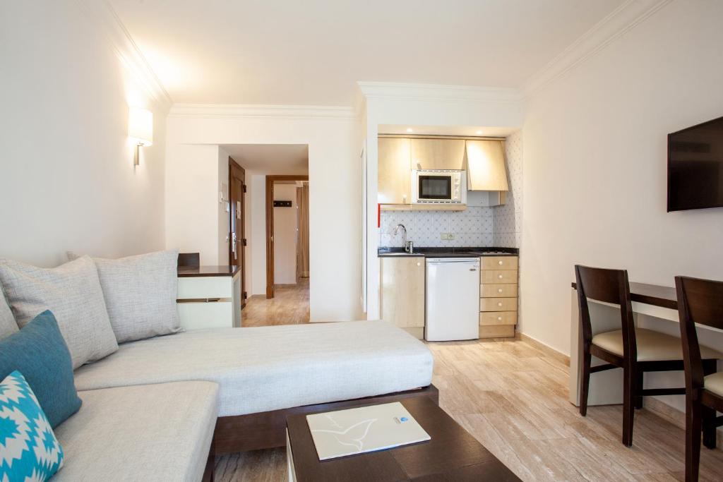 a living room with a couch and a kitchen at Grupotel Los Príncipes & Spa in Playa de Muro