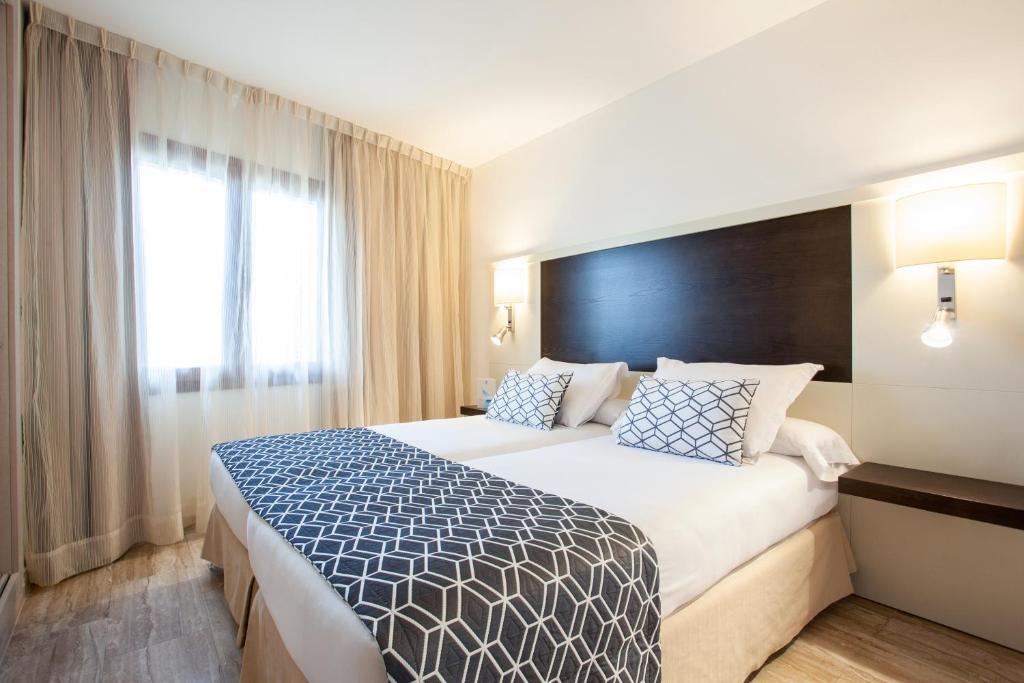 a hotel room with a bed and a window at Grupotel Los Príncipes & Spa in Playa de Muro