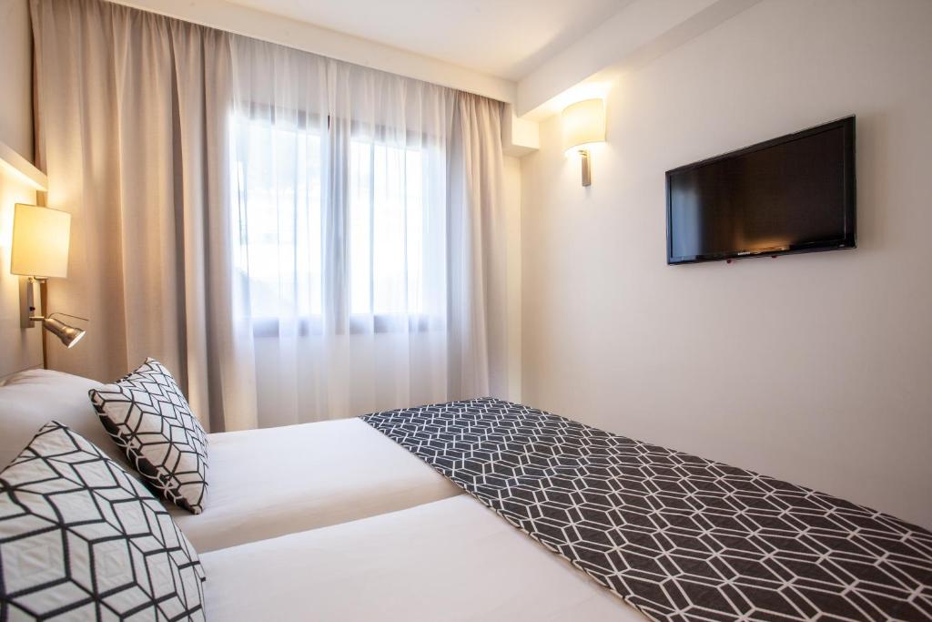 a hotel room with a bed and a flat screen tv at Grupotel Los Príncipes & Spa in Playa de Muro