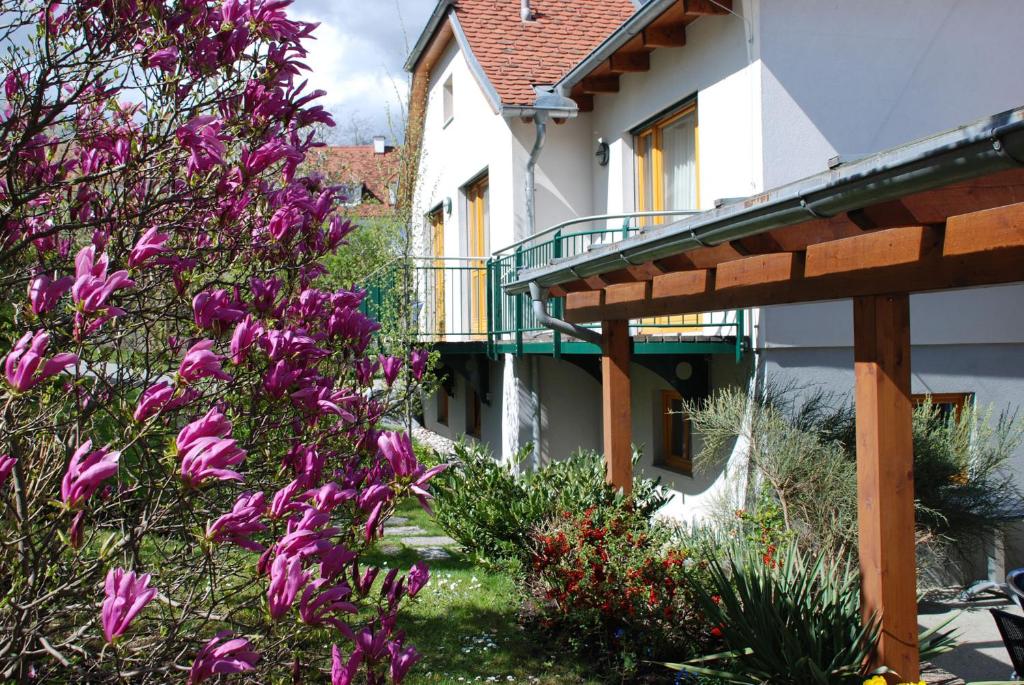 une maison avec des fleurs violettes dans la cour dans l'établissement Pension Christina, à Weiz