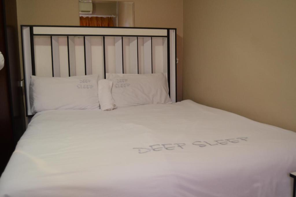 a bed with white sheets and pillows in a room at Sharon Rose Guesthouse in Windhoek