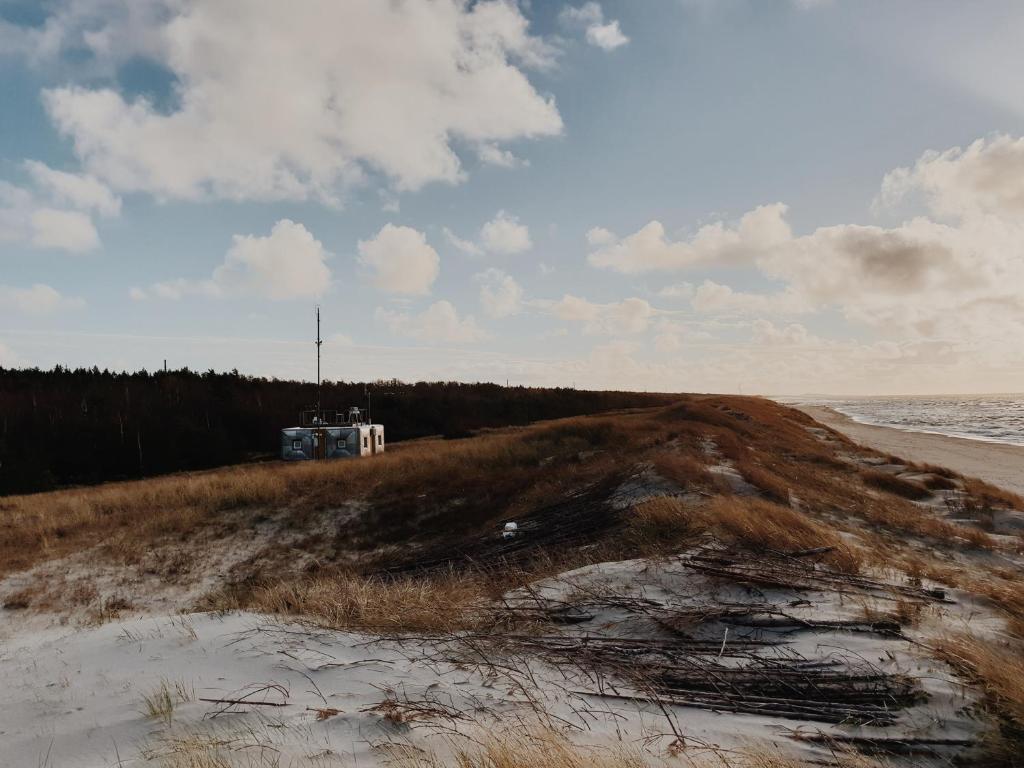 a beach with a house in the sand and the ocean at Amber Ambient Apartments in Juodkrantė