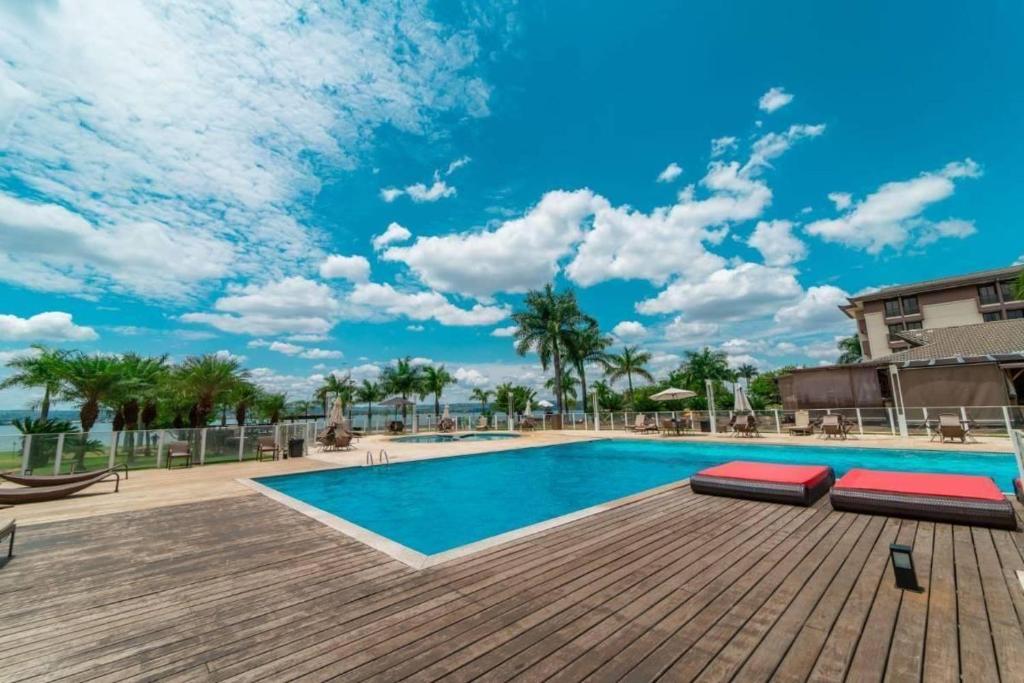 a swimming pool with a wooden deck and a blue sky at Life Resort às margens do lago in Brasília