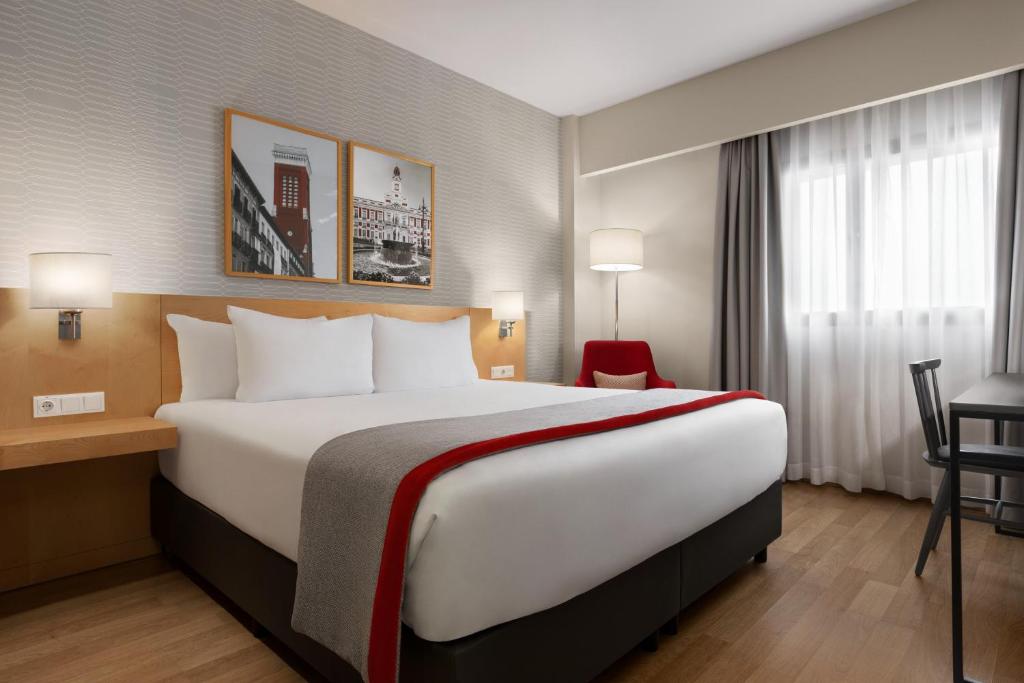 ヘタフェにあるRamada by Wyndham Madrid Getafeの大きなベッドとデスクが備わるホテルルームです。