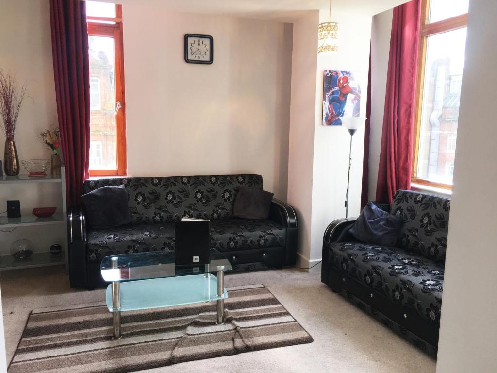 a living room with a black couch and a glass table at Discounted Short Term Let in Manchester