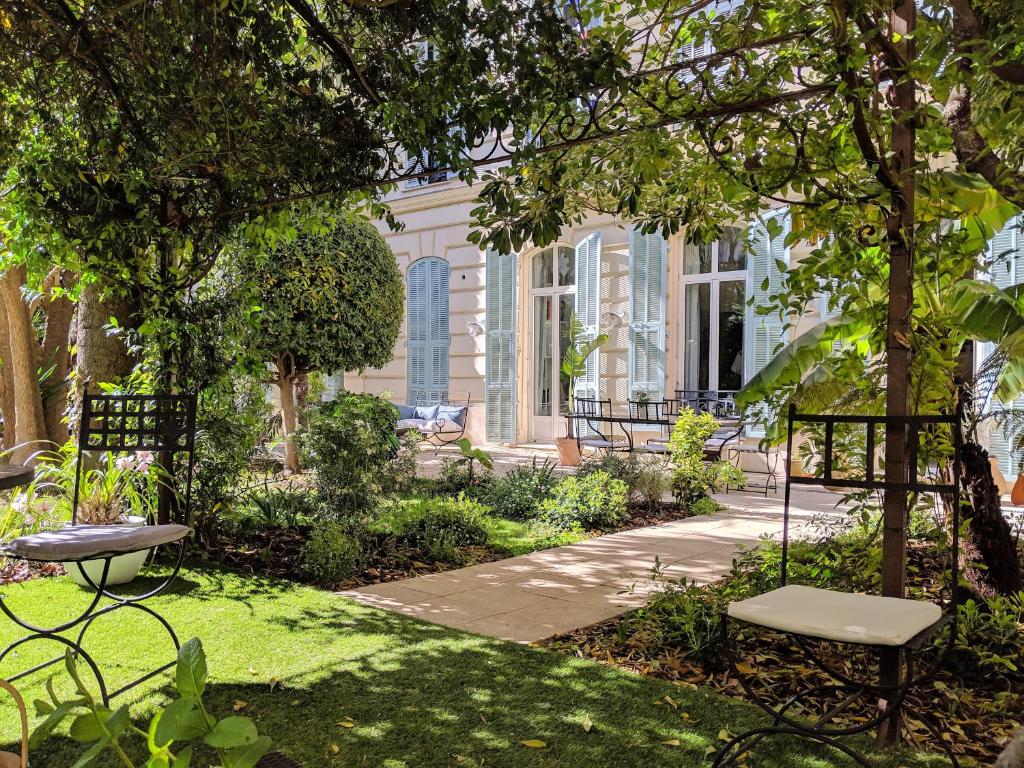 un jardin avec deux bancs et des arbres ainsi qu'un bâtiment dans l'établissement Chambres d'hôtes CASA MUSA - NICE, à Nice