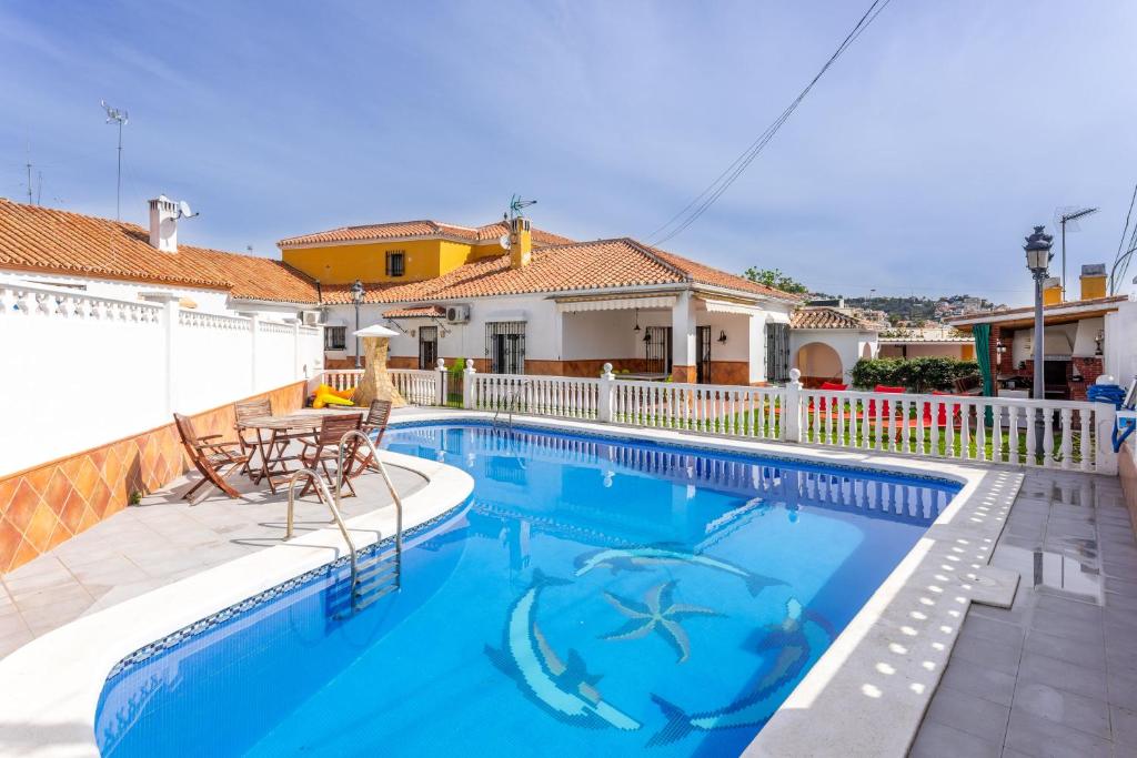 a swimming pool with a table and chairs next to a house at Villa Mascota Rincón de la Victoria in Rincón de la Victoria