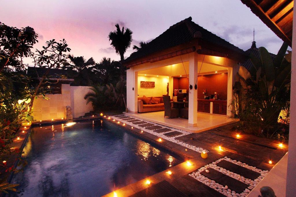 a swimming pool with lights in front of a house at Villa Bali Zen Kerobokan in Kerobokan