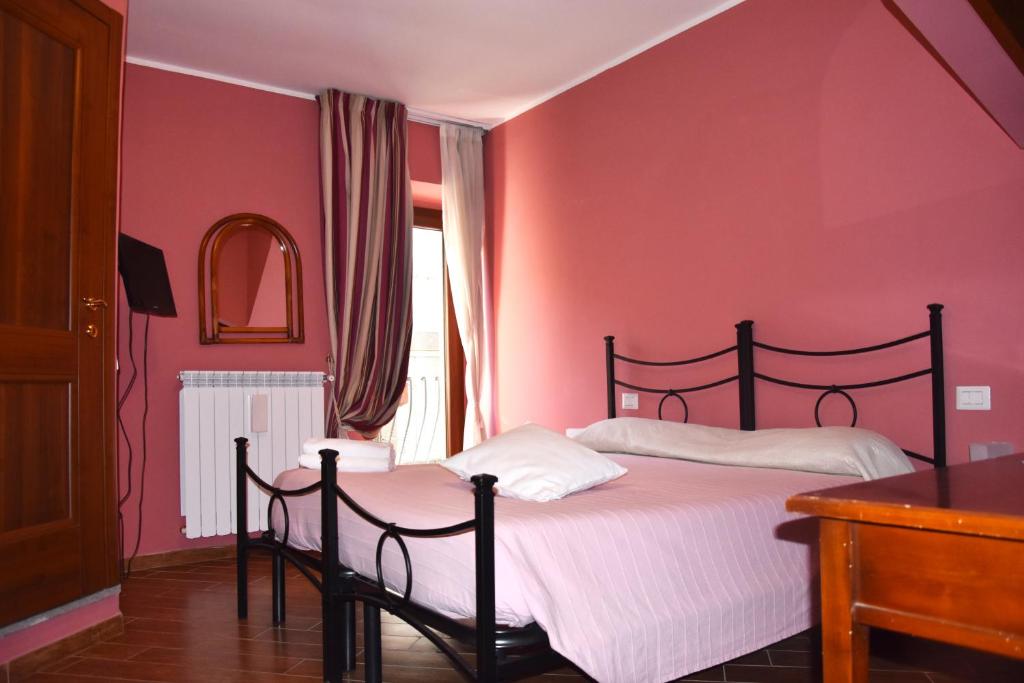 Schlafzimmer mit rosa Wänden und einem Bett mit weißer Bettwäsche in der Unterkunft Il Peperino GuestHouse in Viterbo