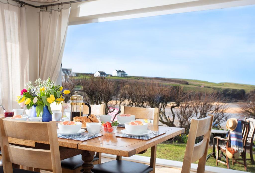 a dining room table with a view of the ocean at Trewalder in St Merryn