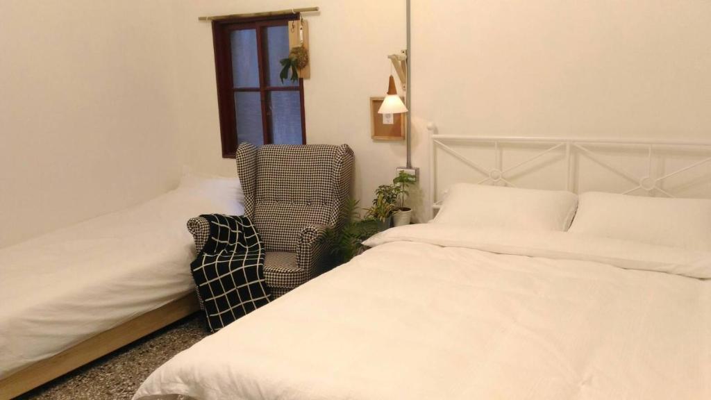 a bedroom with two beds and a chair and a window at i老宅 in Tainan