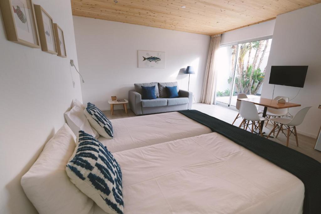 a bedroom with a large white bed and a couch at Sao Vicente Lodge - Atlantic Retreat in São Vicente Ferreira
