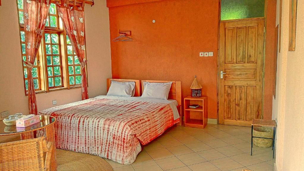 a bedroom with a bed with an orange wall at Kilimanjaro Eco Lodge in Usa River