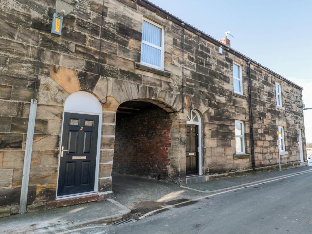 un vieux bâtiment en briques avec une porte et une rue dans l'établissement Mariners Rest, à Morpeth